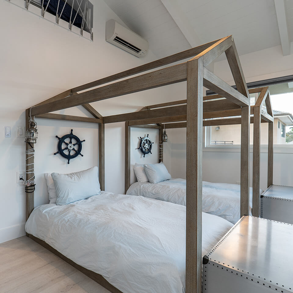 Cozy bedroom with two beds and a wooden canopy, reflecting the peaceful atmosphere of Sea of Glass Hawaii.